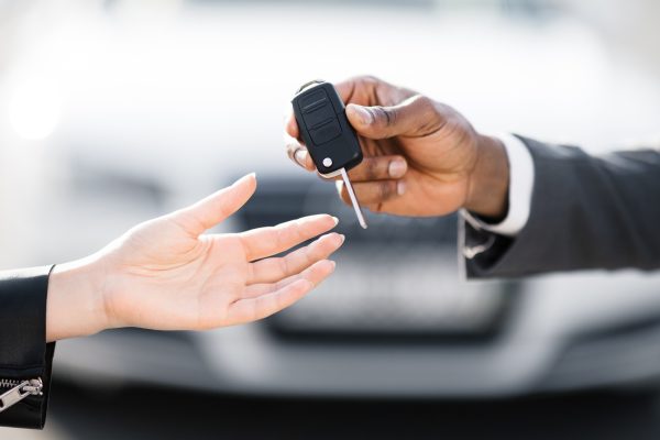 Car sale. Dealer giving key to new owner